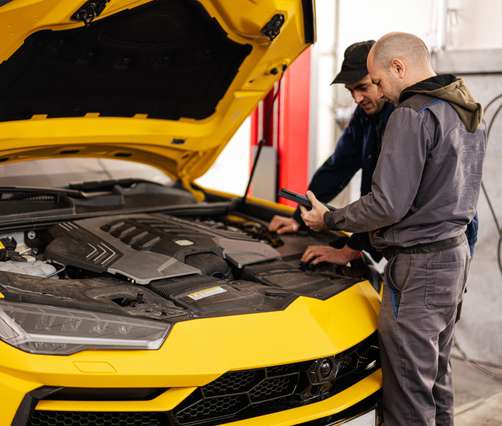 Technicians inspecting a European vehicle with the hood open